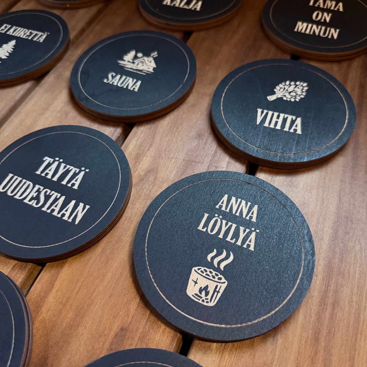Puinen musta sauna-lasinalunen tekstillä Anna löylyä